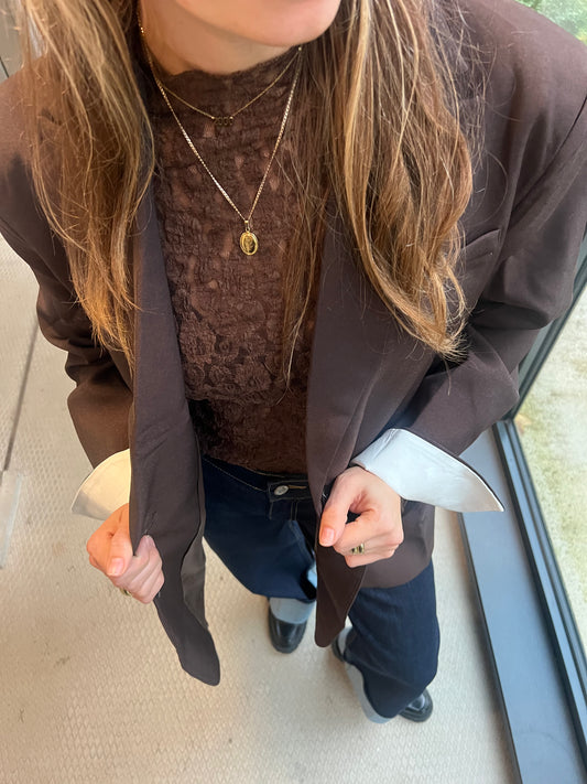 Das Model trägt einen dunkelbraunen Chloe Blazer von Dutch Atelier, den sie mit einem Spitzen-Top kombiniert hat.