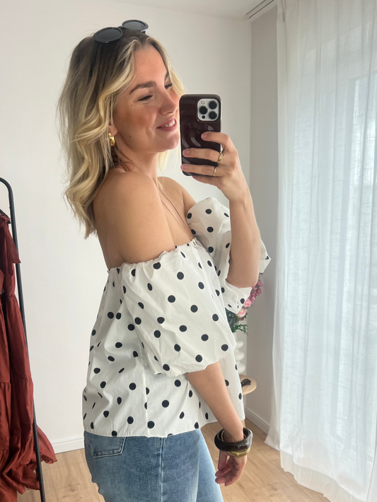 Seitenansicht eines Models in der eleganten Off-Shoulder Polkadot Top Pien in Weiß mit schwarzen Polkadots