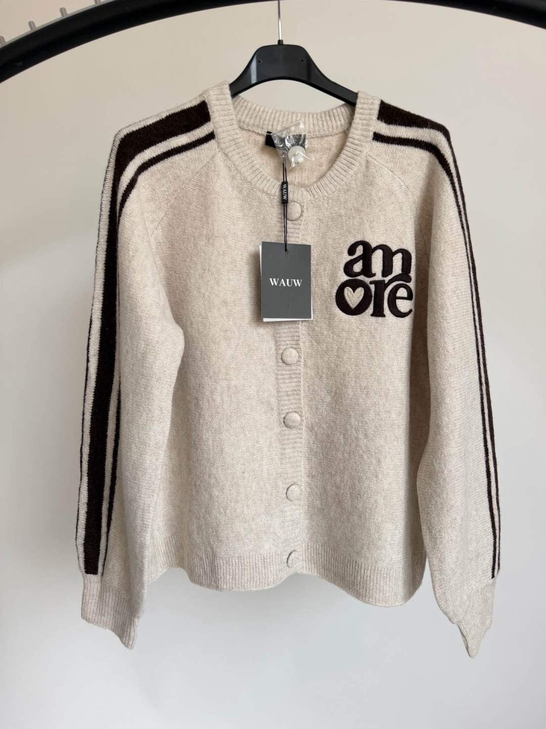 Beige Strickjacke mit braunen Details und Amore-Stickerei. 