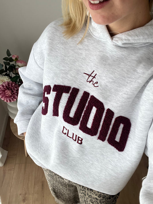 Studio Club Hoodie, Model Bild, Grauer Hoodie mit Bordeaux Text: "The Studio Club"