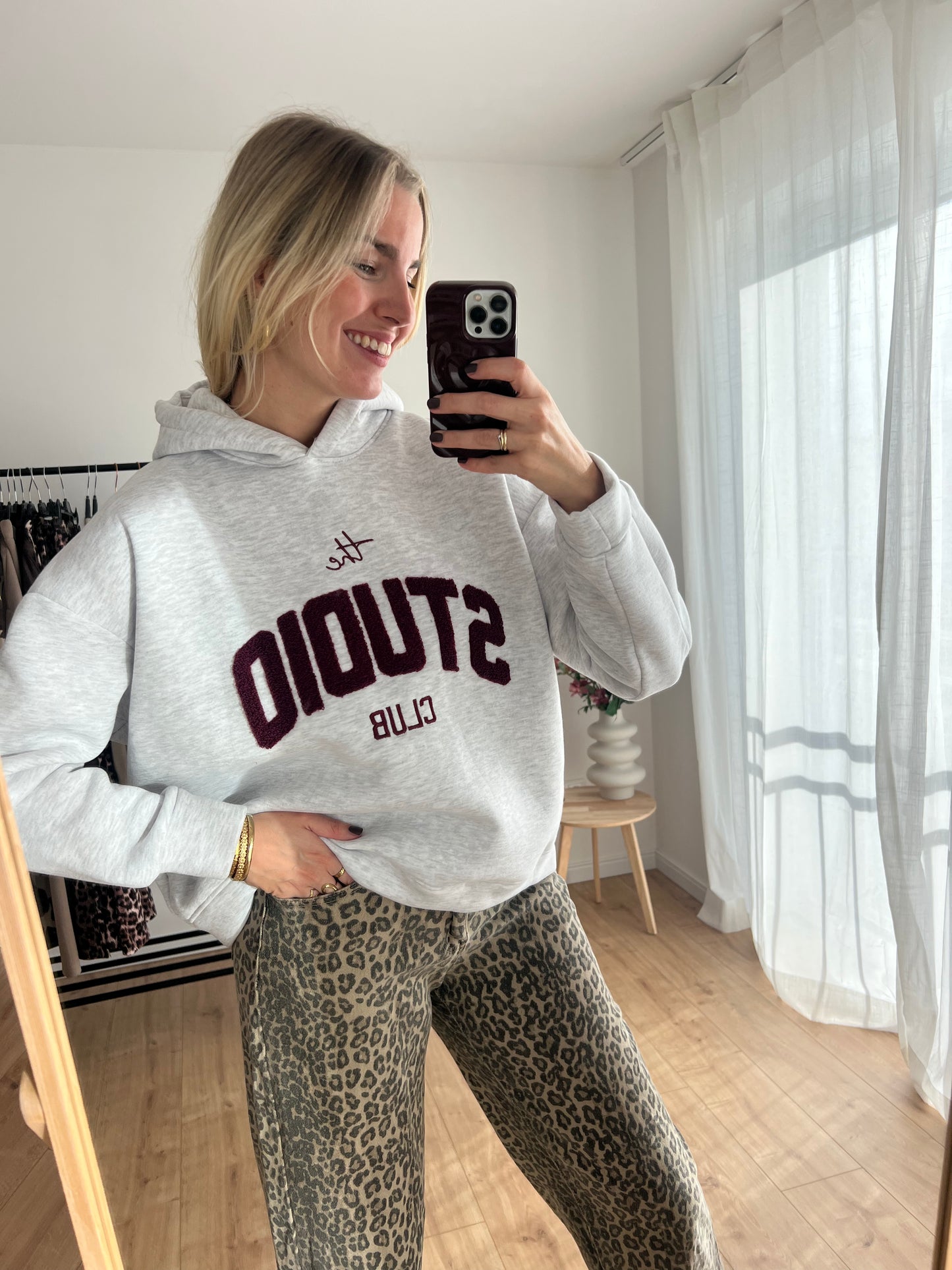 Studio Club Hoodie, Model Bild, Grauer Hoodie mit Bordeaux Text: "The Studio Club"
