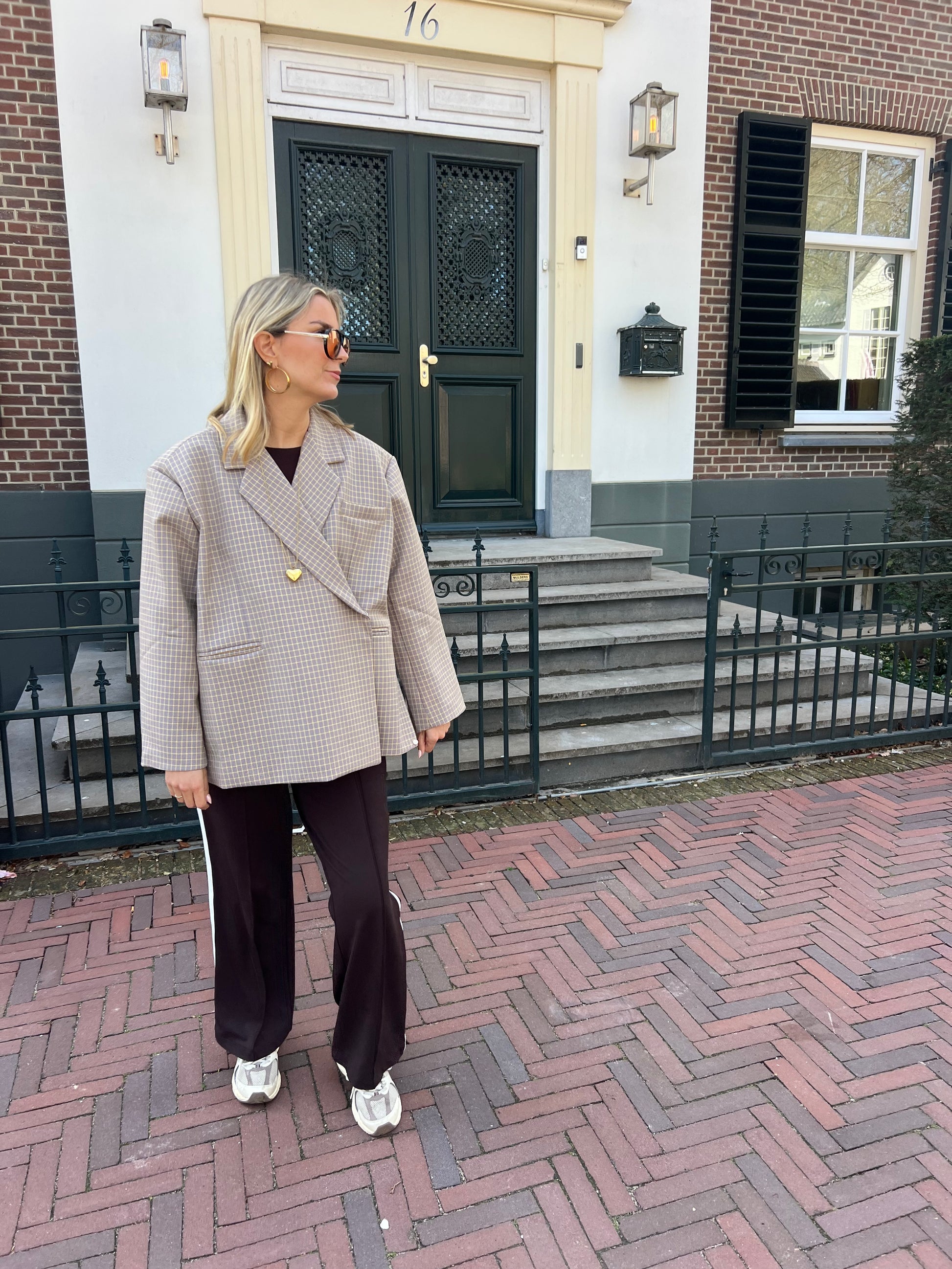 Beiger karierter Blazer mit feinem gelben Streifen von Jasmijn Dutch Atelier, getragen von einem Model in urbaner Umgebung in den Niederlanden.