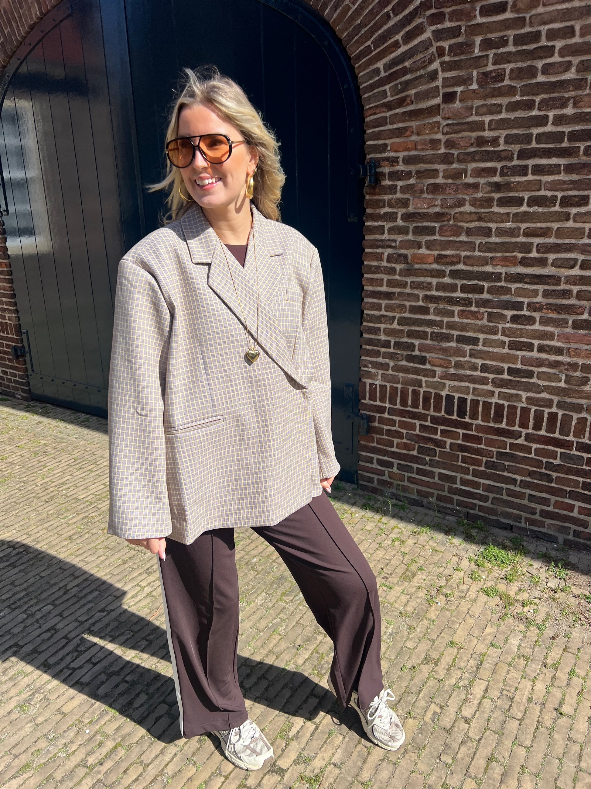 Eleganter Damenblazer in Beige mit gelben Karodetails, fotografiert an einem Model auf einer Straße in den Niederlanden.