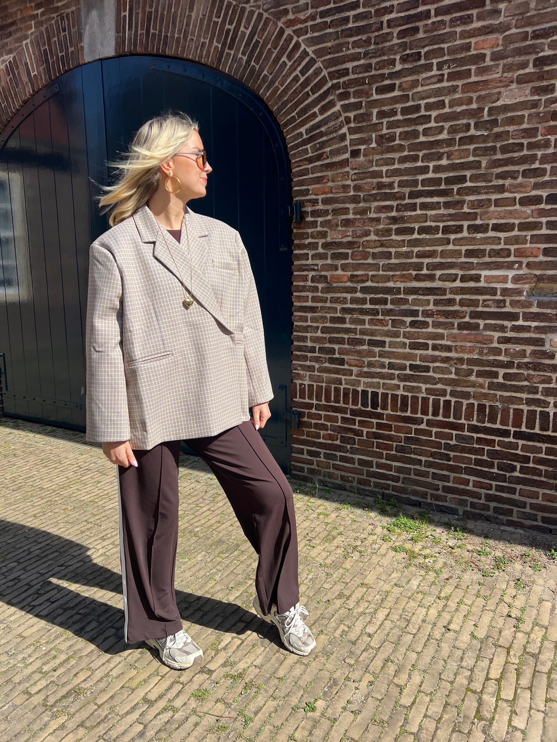 Moderner Blazer von Jasmijn Dutch Atelier in Beige mit gelbem Karomuster, gestylt an einem Model im Outdoor-Shooting in den Niederlanden.