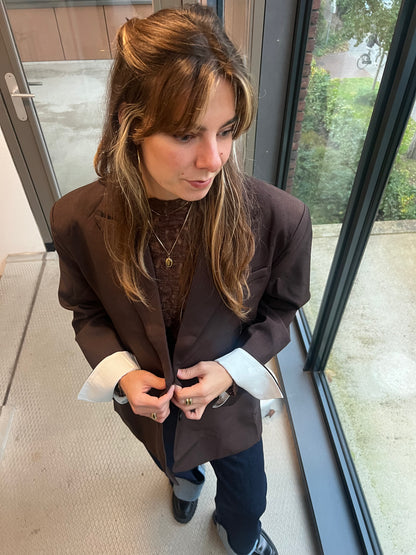 Das Model trägt einen dunkelbraunen Chloe Blazer, von Dutch Atelier, den sie mit einem Spitzen-Top kombiniert hat. 