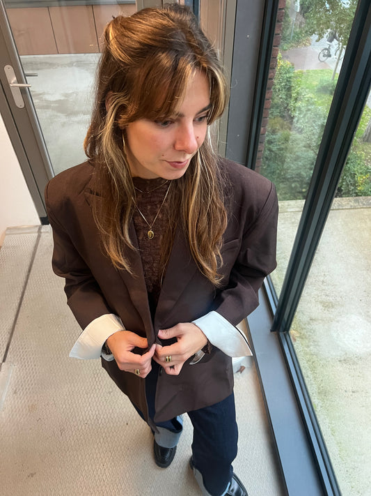 Das Model trägt einen dunkelbraunen Chloe Blazer, von Dutch Atelier, den sie mit einem Spitzen-Top kombiniert hat. 