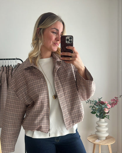 Seitenansicht eines Models mit karierter Bomberjacke kombiniert mit T-Shirt und Jeans